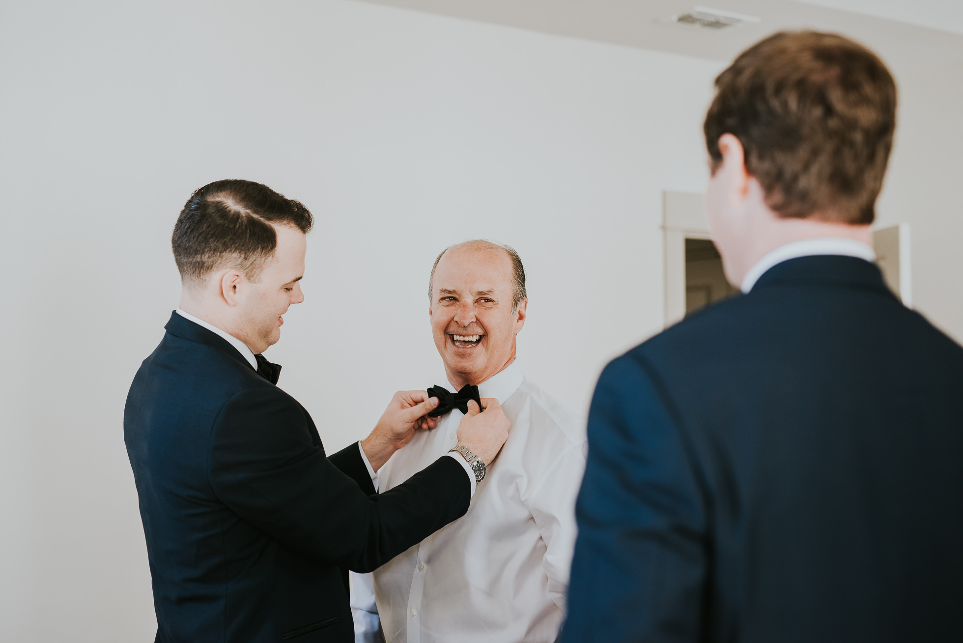 groom tying bowtie for dad