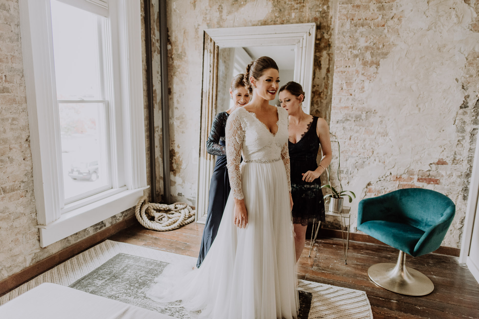 bride getting dress on with mom and sister the cordelle