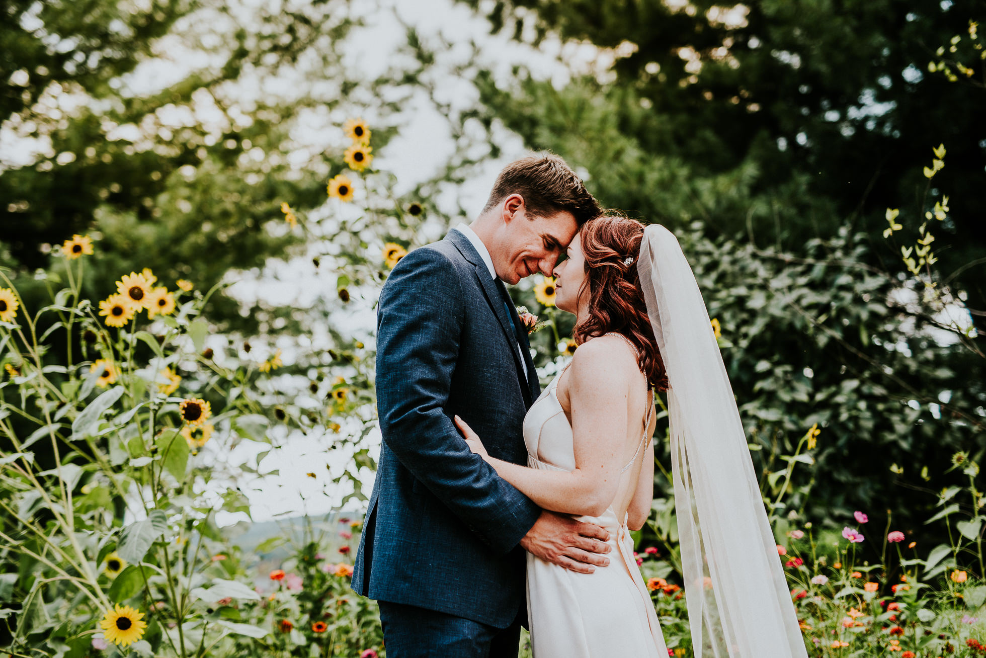bride and groom emotional portrait by flowers at olde tater barn wedding in central bridge, ny photographed by traverse the tides