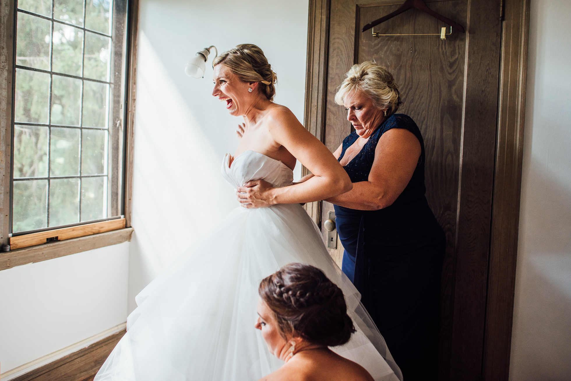 bride putting dress on with mom and sister at lyndhurst castle photographed by traverse the tides-2