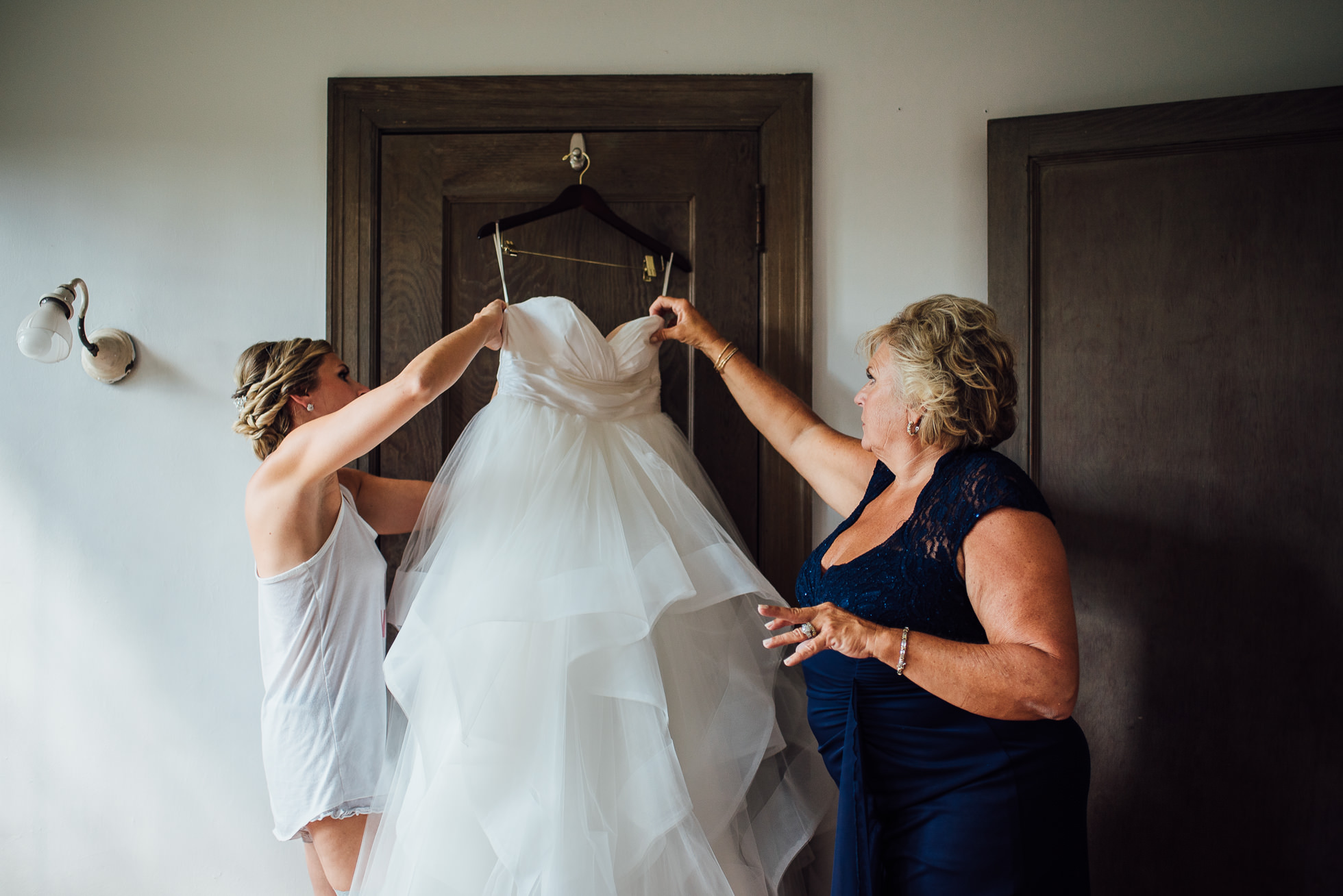 bride putting dress on with mom at lyndhurst castle photographed by traverse the tides