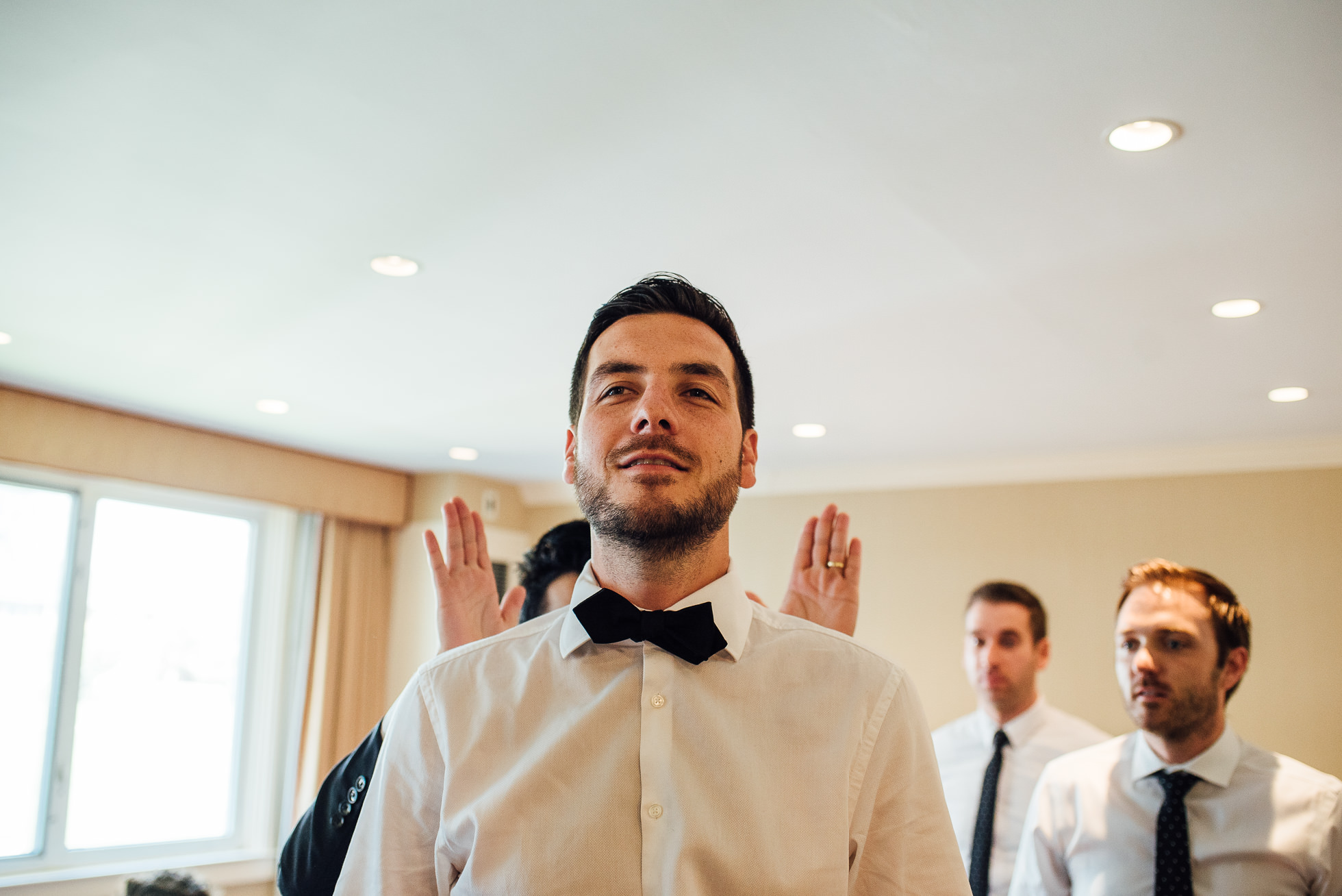 groom putting on bowtie at lyndhurst castle wedding photographed by traverse the tides