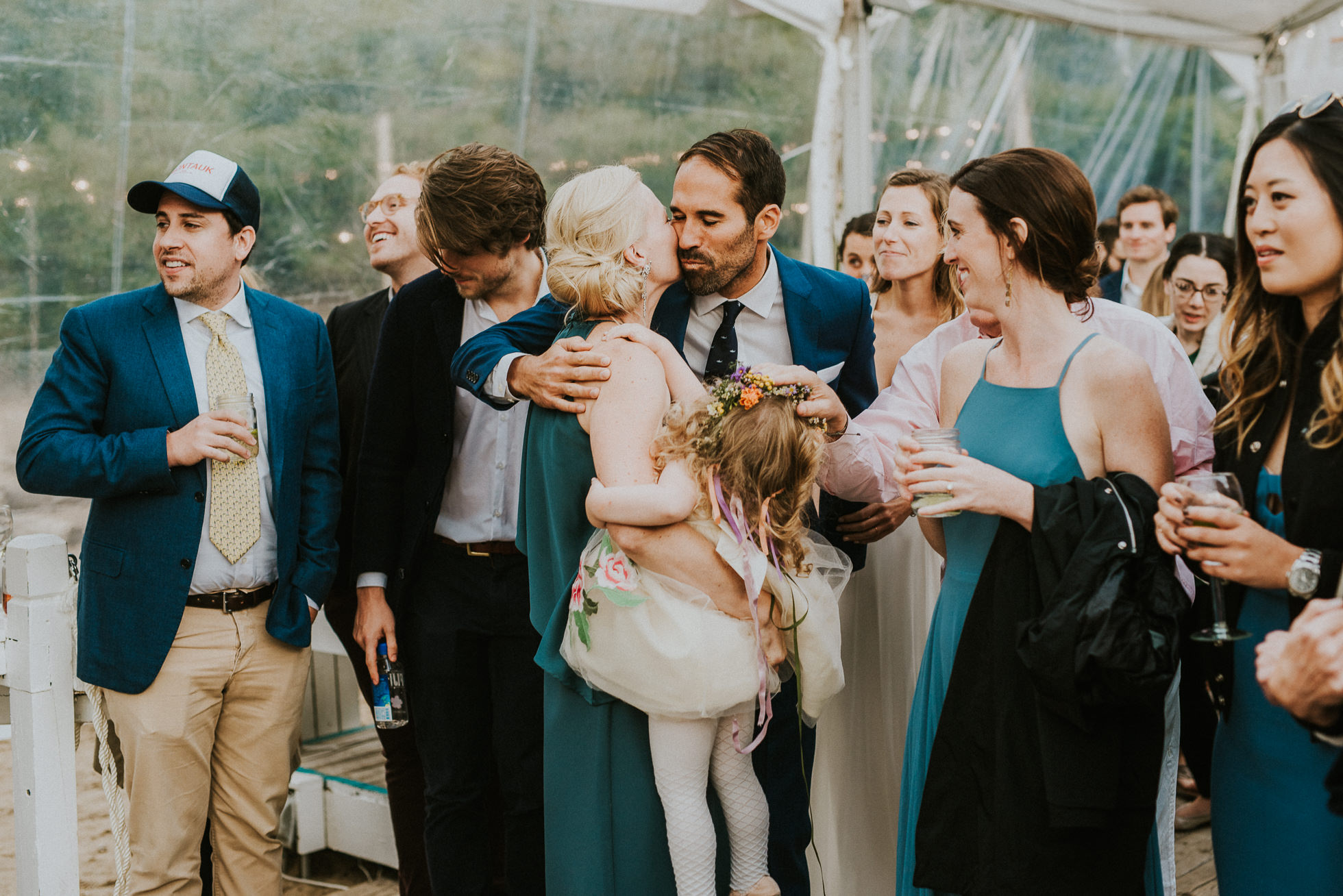 bride and groom kissing maid of honor at the surf lodge in Montauk wedding photographed by Traverse the Tides