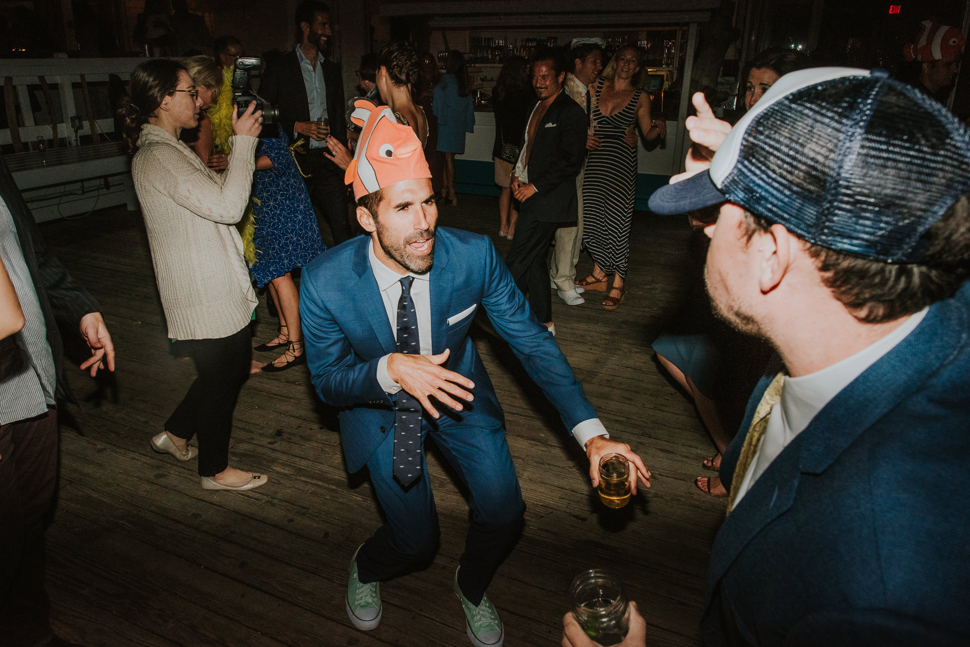 groom with funny hat at reception Montauk wedding photographed by Traverse the Tides